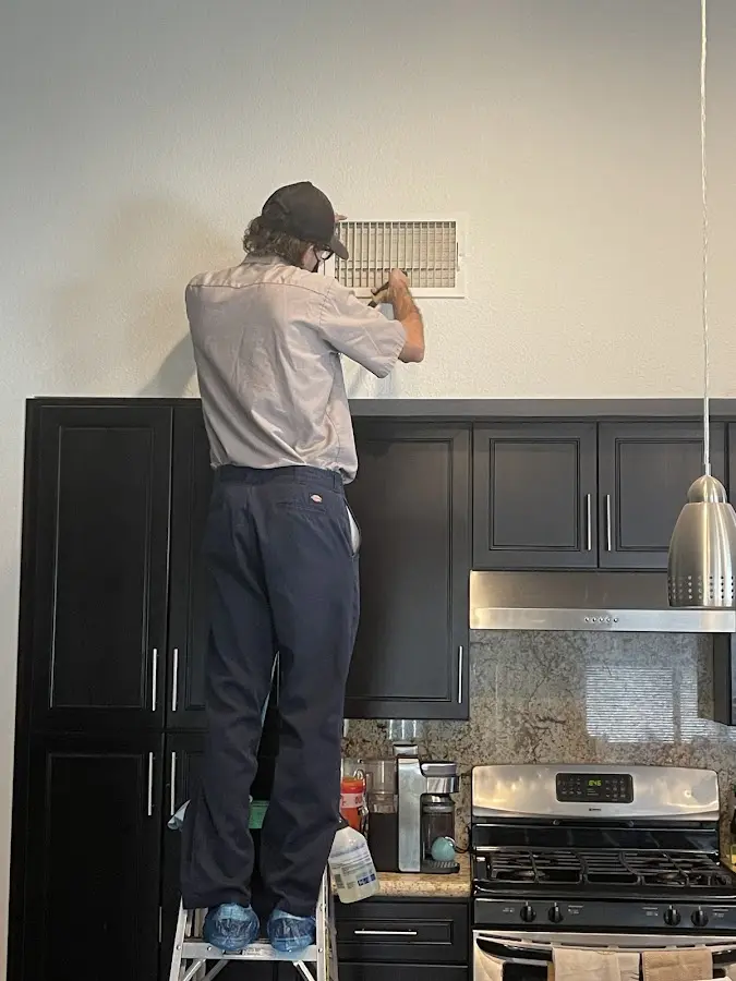 Technician inspecting an air vent during HVAC service in Pleasant Grove